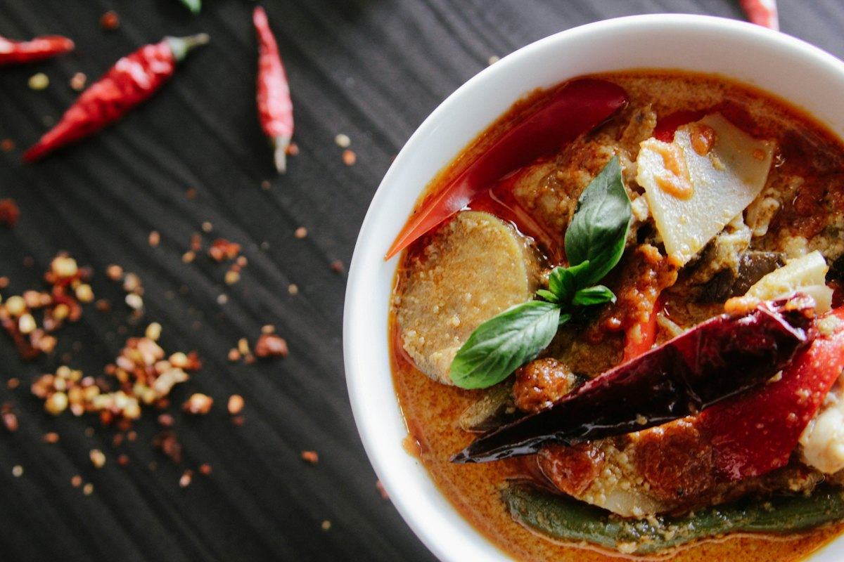 A bowl of red curry with chillies and herbs